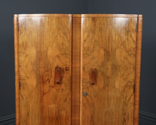 fig 5. An Art Deco walnut two door wardrobe featuring a bow front design, carved wood handles, and figured timber grain.