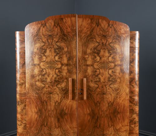 fig 1. An Art Deco two door wardrobe crafted from warm brown figured walnut veneer with a gently curved bow front and wooden vertical handles.