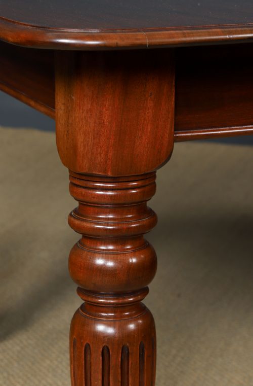 fig 2. A Victorian mahogany extending dining table with a rectangular top, rounded corners, and turned fluted legs set on brass castors.