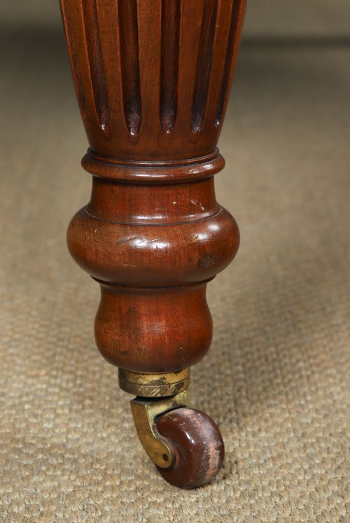 fig 3. A Victorian mahogany extending dining table with a rectangular top, rounded corners, and turned fluted legs set on brass castors.