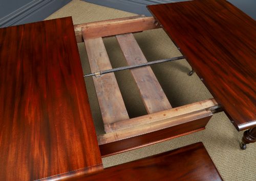 fig 4. A Victorian mahogany extending dining table with a rectangular top, rounded corners, and turned fluted legs set on brass castors.