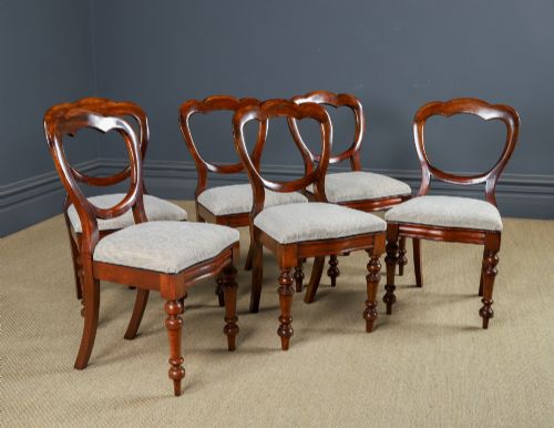 fig 2. A set of six Victorian mahogany dining chairs featuring open balloon-shaped backs, turned front legs, and neutral upholstered seats.