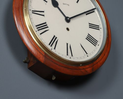 fig 1. An antique Smiths circular wall clock with a turned mahogany surround, off-white dial plate, black Roman numerals, and brass bezel.