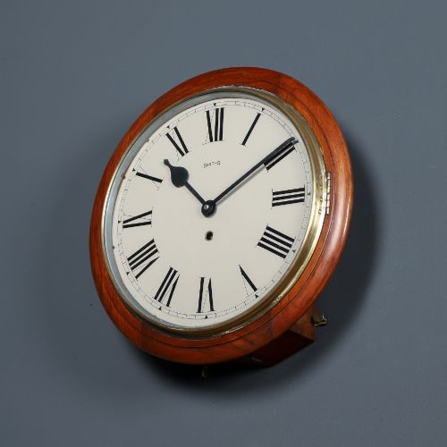 fig 2. An antique Smiths circular wall clock with a turned mahogany surround, off-white dial plate, black Roman numerals, and brass bezel.