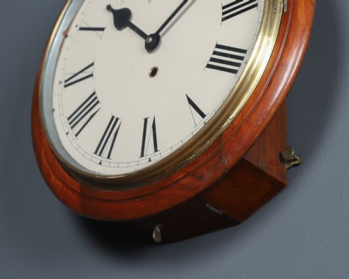 fig 3. An antique Smiths circular wall clock with a turned mahogany surround, off-white dial plate, black Roman numerals, and brass bezel.
