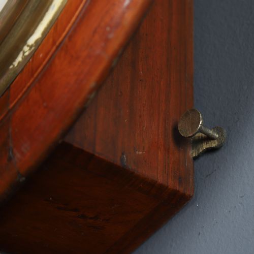fig 5. An antique Smiths circular wall clock with a turned mahogany surround, off-white dial plate, black Roman numerals, and brass bezel.
