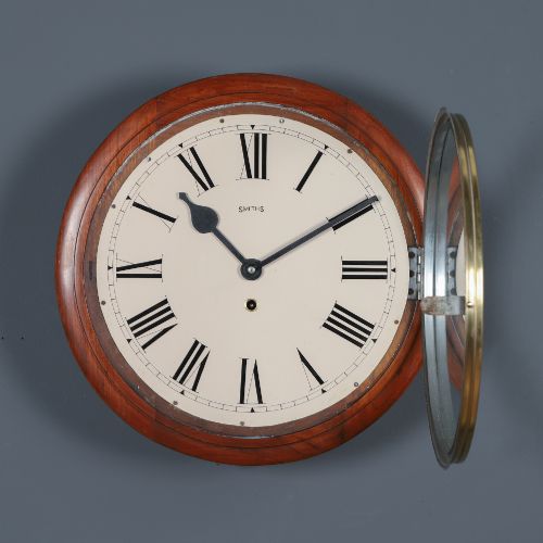fig 6. An antique Smiths circular wall clock with a turned mahogany surround, off-white dial plate, black Roman numerals, and brass bezel.