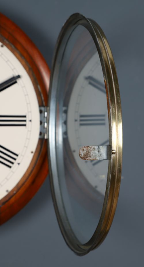 fig 7. An antique Smiths circular wall clock with a turned mahogany surround, off-white dial plate, black Roman numerals, and brass bezel.