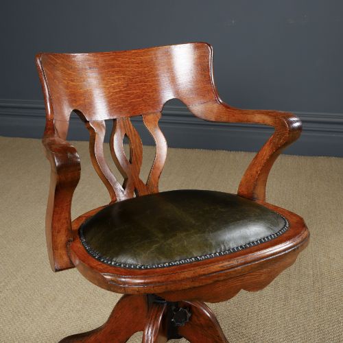 fig 1. An Edwardian oak revolving desk armchair featuring a carved pierced back splat, green leather upholstered seat with close studding, and a four-point swivel base on brass castors.