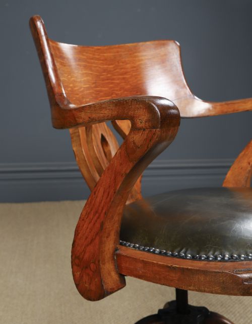 fig 5. An Edwardian oak revolving desk armchair featuring a carved pierced back splat, green leather upholstered seat with close studding, and a four-point swivel base on brass castors.