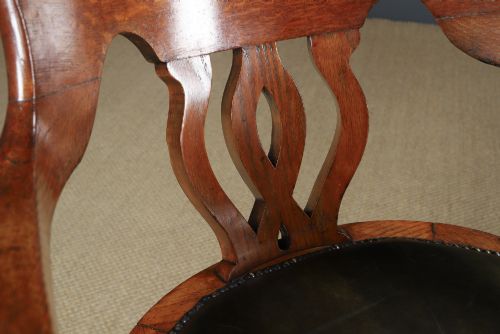 fig 7. An Edwardian oak revolving desk armchair featuring a carved pierced back splat, green leather upholstered seat with close studding, and a four-point swivel base on brass castors.