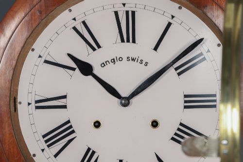 fig 2. A circular antique wall clock featuring a turned mahogany frame, brass bezel, and white dial with black Roman numerals marked Anglo Swiss.