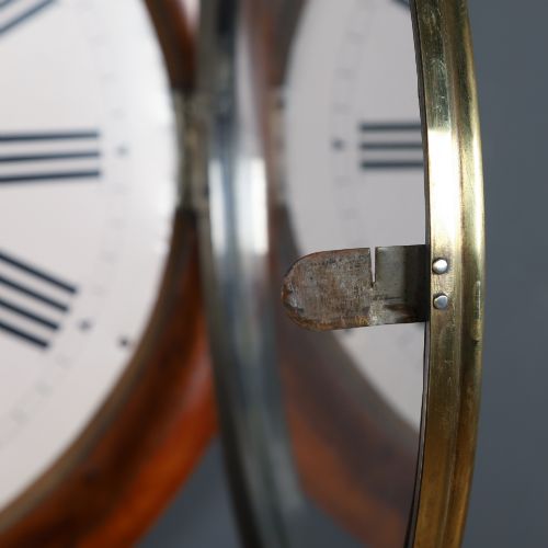 fig 4. A circular antique wall clock featuring a turned mahogany frame, brass bezel, and white dial with black Roman numerals marked Anglo Swiss.