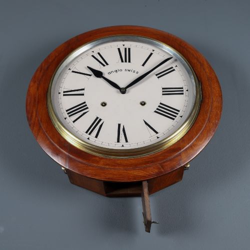 fig 5. A circular antique wall clock featuring a turned mahogany frame, brass bezel, and white dial with black Roman numerals marked Anglo Swiss.