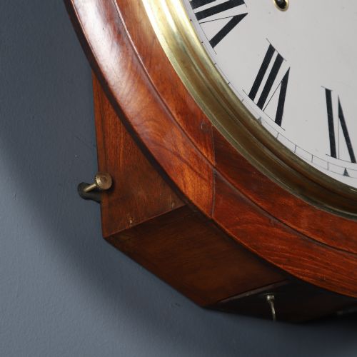 fig 6. A circular antique wall clock featuring a turned mahogany frame, brass bezel, and white dial with black Roman numerals marked Anglo Swiss.