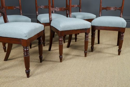 fig 2. A set of six antique mahogany dining chairs featuring curved top rails, carved horizontal splats, fluted turned front legs, and light blue upholstered seats.