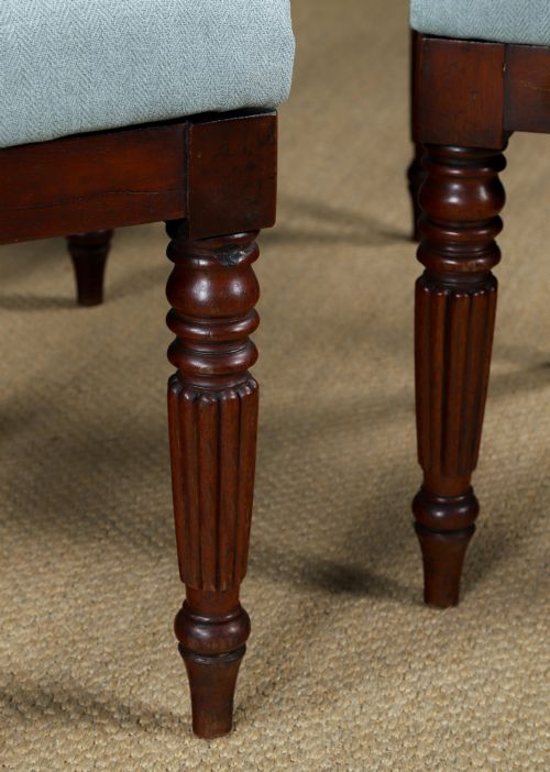 fig 6. A set of six antique mahogany dining chairs featuring curved top rails, carved horizontal splats, fluted turned front legs, and light blue upholstered seats.
