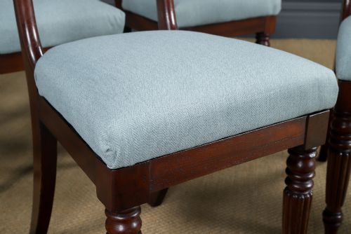 fig 7. A set of six antique mahogany dining chairs featuring curved top rails, carved horizontal splats, fluted turned front legs, and light blue upholstered seats.
