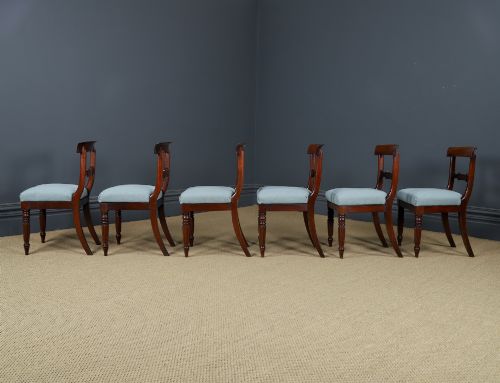 fig 10. A set of six antique mahogany dining chairs featuring curved top rails, carved horizontal splats, fluted turned front legs, and light blue upholstered seats.