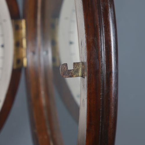 fig 2. A circular mahogany wall clock with a cream dial, black Arabic numerals, black metal hands, two brass winding holes, and the Enfield maker name printed in the centre.