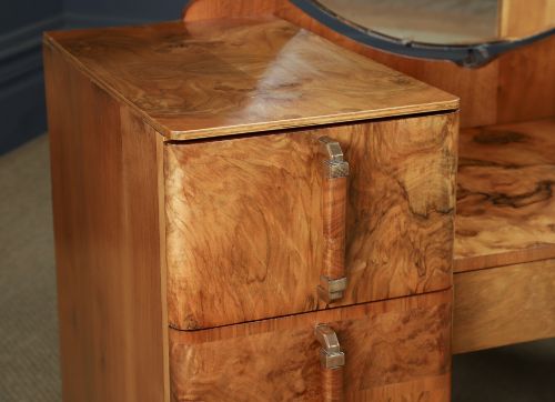 fig 2. An Art Deco burr walnut pedestal dressing table featuring a large circular central mirror, a kneehole drawer, and three stacked drawers on each pedestal with vertical handles.