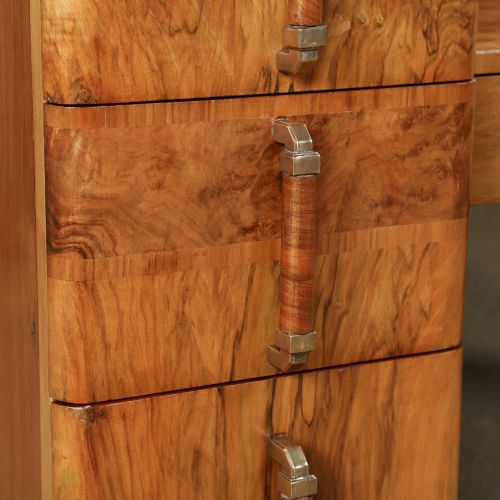 fig 3. An Art Deco burr walnut pedestal dressing table featuring a large circular central mirror, a kneehole drawer, and three stacked drawers on each pedestal with vertical handles.