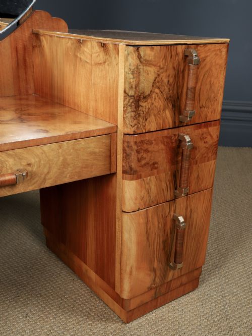 fig 4. An Art Deco burr walnut pedestal dressing table featuring a large circular central mirror, a kneehole drawer, and three stacked drawers on each pedestal with vertical handles.