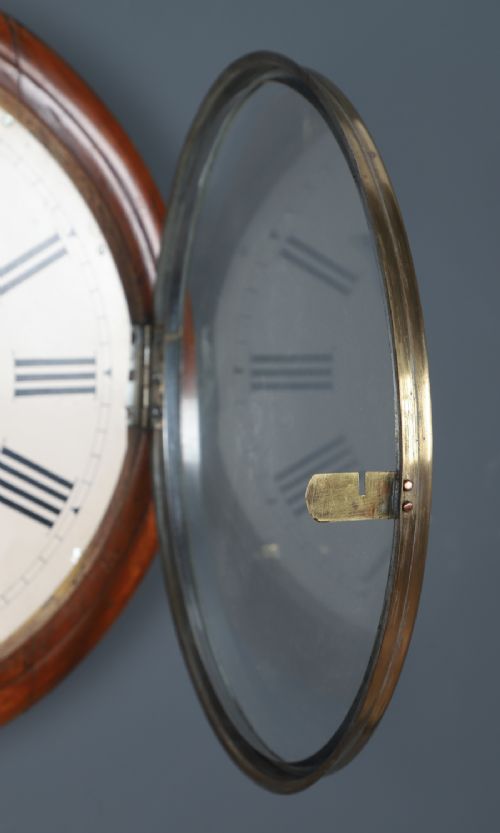 fig 3. A circular Smiths antique wall clock with a turned mahogany wood surround, off-white dial with black Roman numerals, brass hinged bezel, and winding holes.