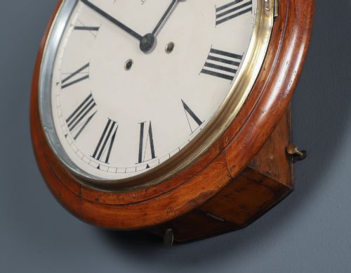 fig 7. A circular Smiths antique wall clock with a turned mahogany wood surround, off-white dial with black Roman numerals, brass hinged bezel, and winding holes.
