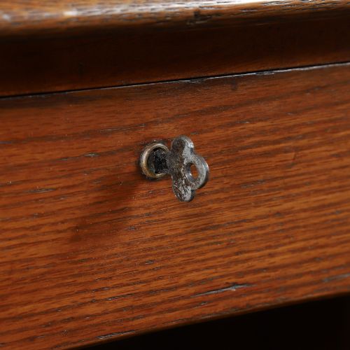 fig 4. An Edwardian warm brown oak twin-pedestal rolltop desk featuring a flexible slatted wooden tambour shutter open to reveal internal pigeonholes above nine drawers with wooden cup handles.