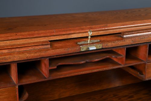 fig 5. An Edwardian warm brown oak twin-pedestal rolltop desk featuring a flexible slatted wooden tambour shutter open to reveal internal pigeonholes above nine drawers with wooden cup handles.