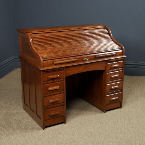 fig 9. An Edwardian warm brown oak twin-pedestal rolltop desk featuring a flexible slatted wooden tambour shutter open to reveal internal pigeonholes above nine drawers with wooden cup handles.