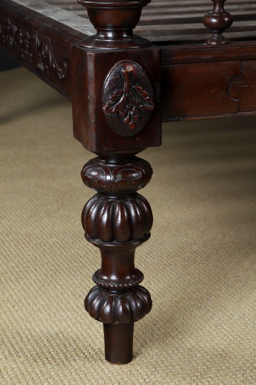 fig 3. An Anglo-Indian mahogany four poster bed featuring carved turned posts, an ornate headboard, and a spindle footboard.