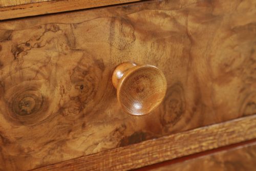 fig 4. An Art Deco chest of drawers in figured burr walnut featuring six graduated drawers with turned wooden handles and carved shoulder details.