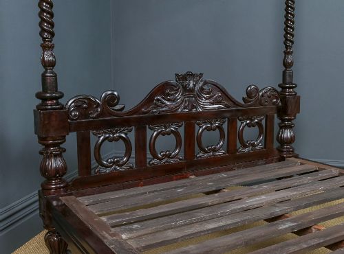 fig 2. An antique dark timber king-size four-poster bed featuring spiral turned posts, a carved footboard with circular cut-out details, and an upper canopy frame.