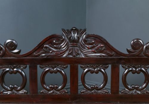fig 3. An antique dark timber king-size four-poster bed featuring spiral turned posts, a carved footboard with circular cut-out details, and an upper canopy frame.