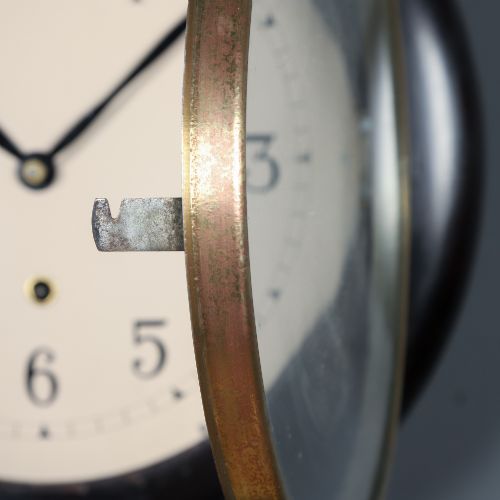 fig 3. A circular antique dark mahogany wall clock featuring a white dial with black Arabic numerals and a brass bezel.