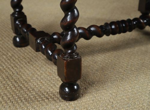 fig 4. An antique 17th-century style dark oak armchair featuring deep-buttoned green leather upholstery, brass stud trim, and barley-twist turned legs and stretchers.