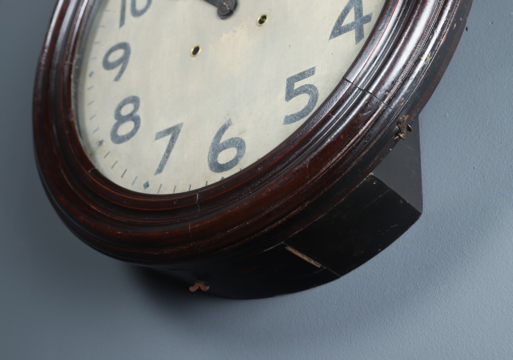 A large circular antique wall clock featuring a dark mahogany wooden surround, an off-white dial with bold black Arabic numerals, and twin winding keyholes. View III