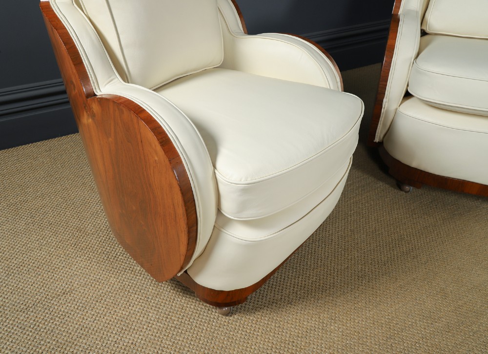 An antique Art Deco three-piece lounge suite consisting of a three-seater sofa and two matching armchairs upholstered in cream leather with curved walnut side panels. View III