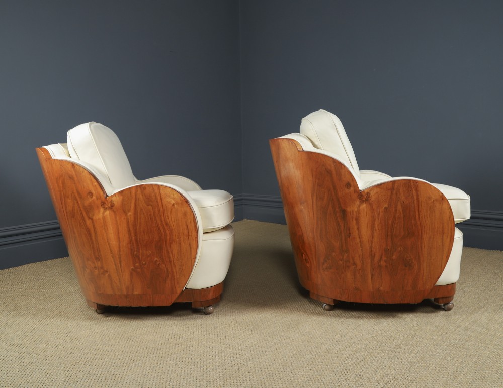 An antique Art Deco three-piece lounge suite consisting of a three-seater sofa and two matching armchairs upholstered in cream leather with curved walnut side panels. View XIV