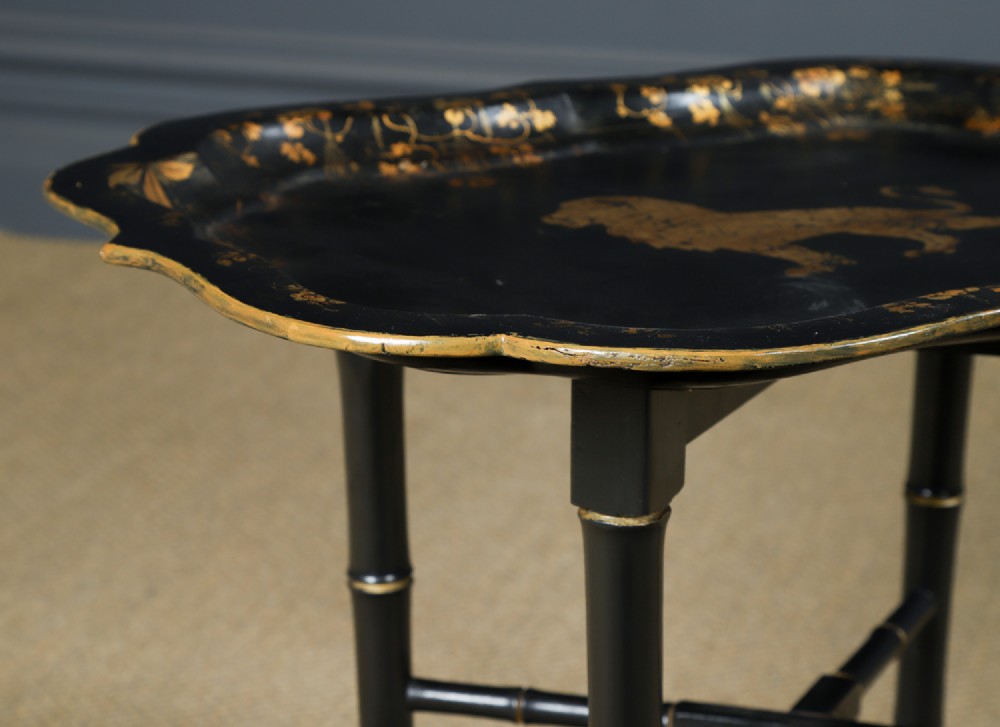 An ebonised Victorian papier-mache tray table featuring gilt Chinoiserie decoration and a lion motif, resting on a faux-bamboo base. View II