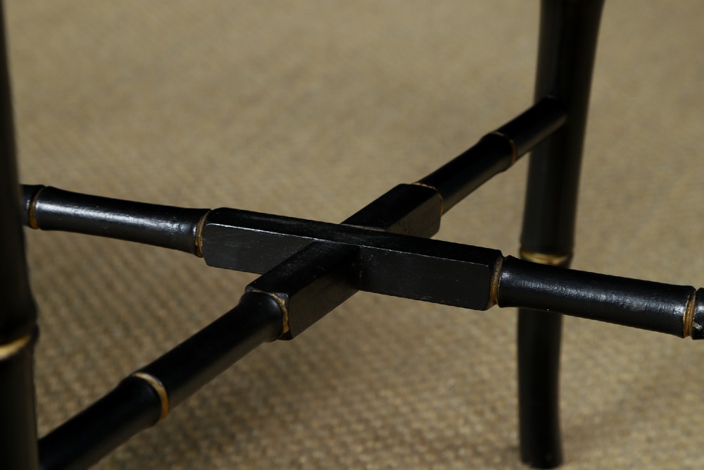 An ebonised Victorian papier-mache tray table featuring gilt Chinoiserie decoration and a lion motif, resting on a faux-bamboo base. View V