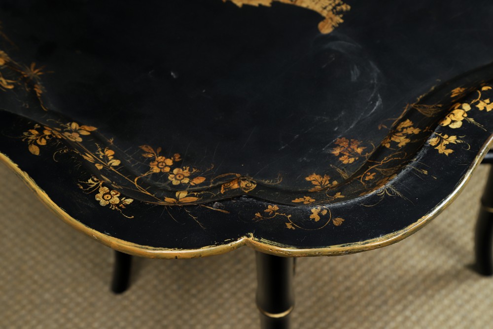 An ebonised Victorian papier-mache tray table featuring gilt Chinoiserie decoration and a lion motif, resting on a faux-bamboo base. View VIII