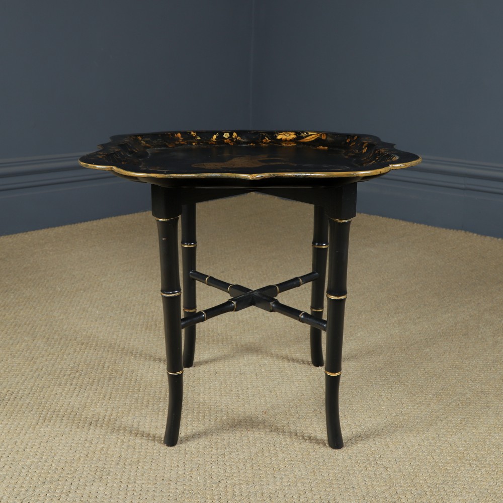 An ebonised Victorian papier-mache tray table featuring gilt Chinoiserie decoration and a lion motif, resting on a faux-bamboo base. View IX