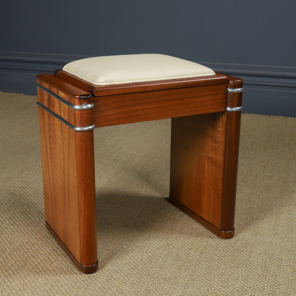 An Art Deco rectangular walnut stool featuring slab legs with metal band accents and a cream leather padded seat. View II