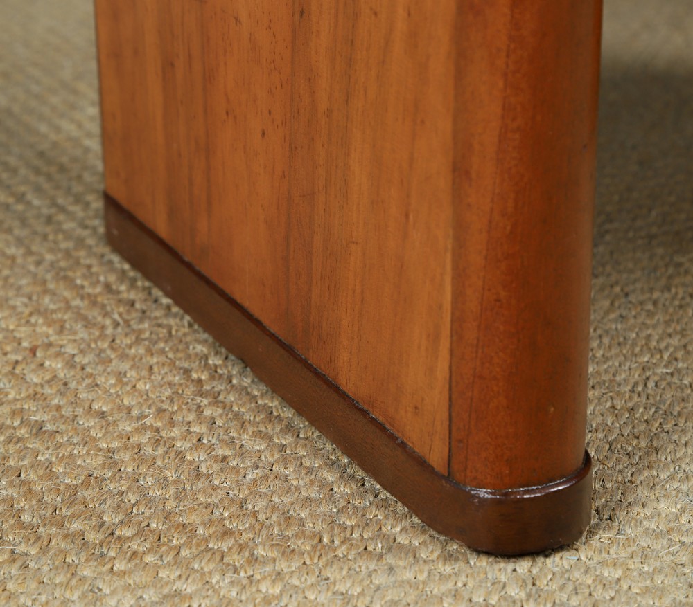 An Art Deco rectangular walnut stool featuring slab legs with metal band accents and a cream leather padded seat. View V