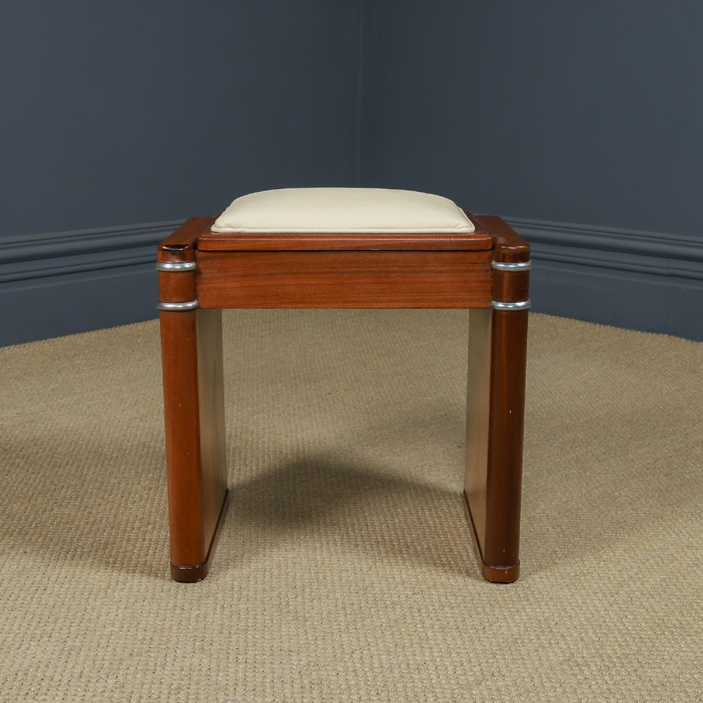 An Art Deco rectangular walnut stool featuring slab legs with metal band accents and a cream leather padded seat. View VII
