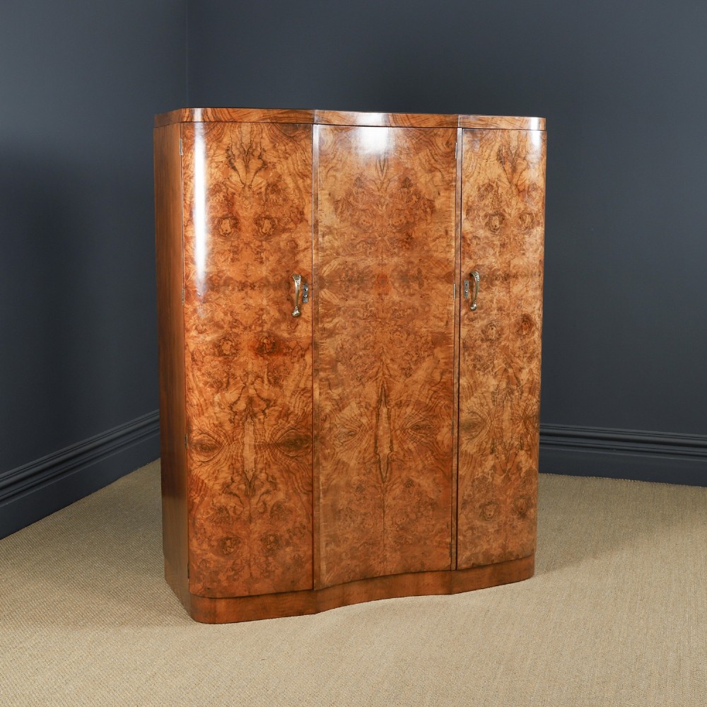 An English Art Deco triple-door wardrobe crafted from figured burr walnut with curved sides and vertical handles.