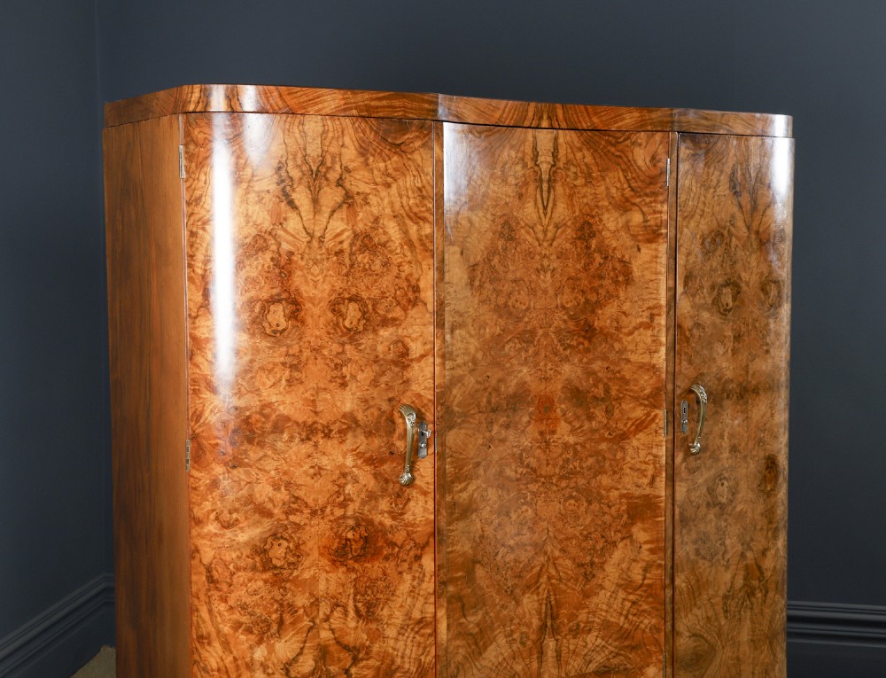 An English Art Deco triple-door wardrobe crafted from figured burr walnut with curved sides and vertical handles. View II